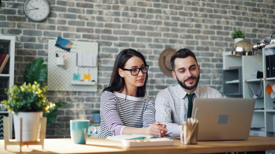 Two young professionals working together in a modern office environment.